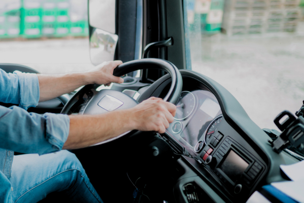 Hands on a steering wheel of a truck.