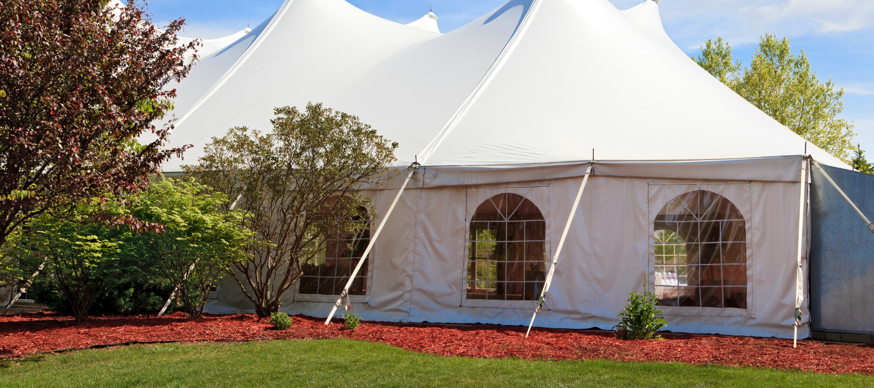 A large white event tent set up outdoors on a clear day.