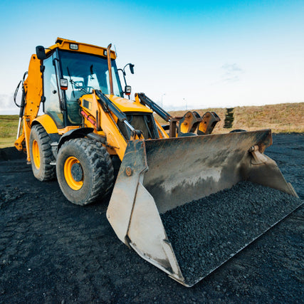 ContractorA loader with a bucket full of gravel parked outside on a clear day.