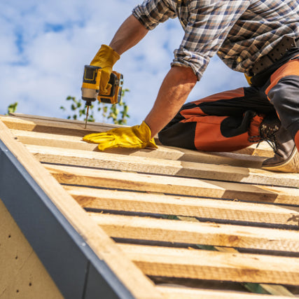 DIYA contractor using a yellow power drill to install studs to a roof.