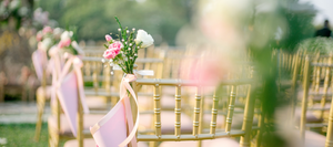 Golden wedding chairs setup and decorated with pink linens and flowers.